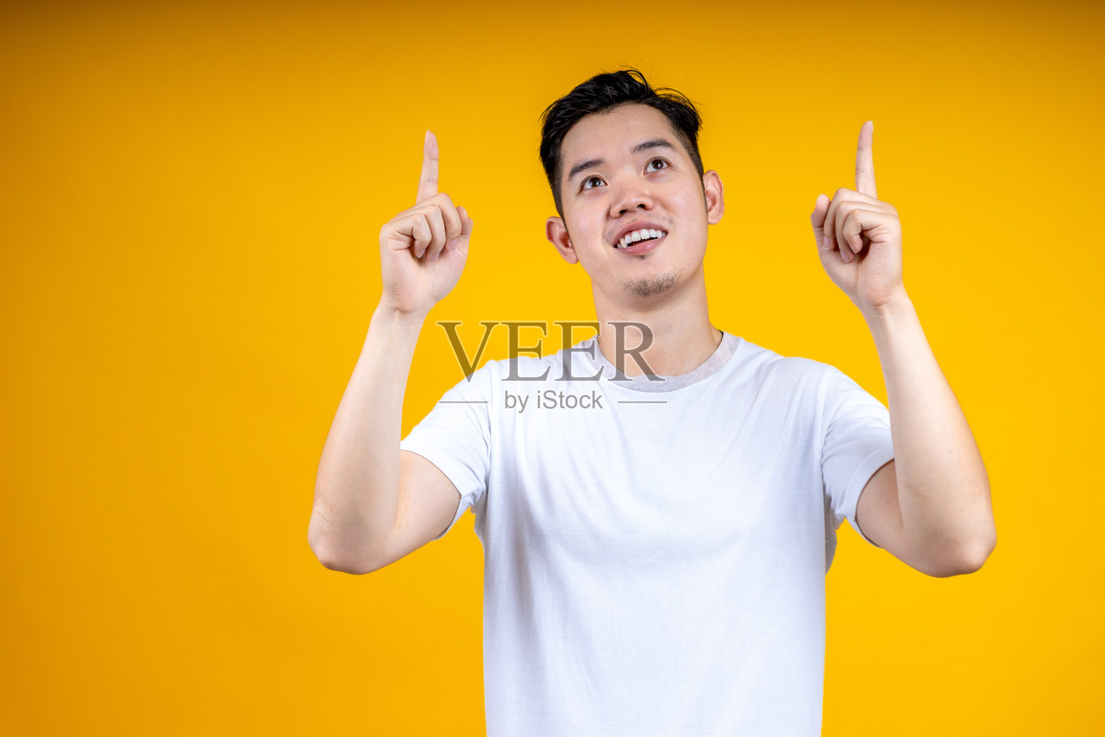 亚洲人摆姿势孤立在黄橙色的背景，工作室肖像。人的情感生活理念。模拟拷贝空间。食指指向，手放在一边。照片摄影图片