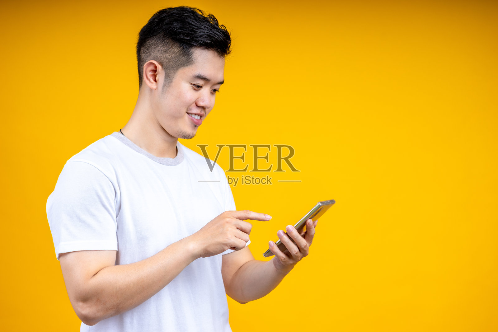 肖像亚洲年轻男子看手机孤立在黄色背景。照片摄影图片