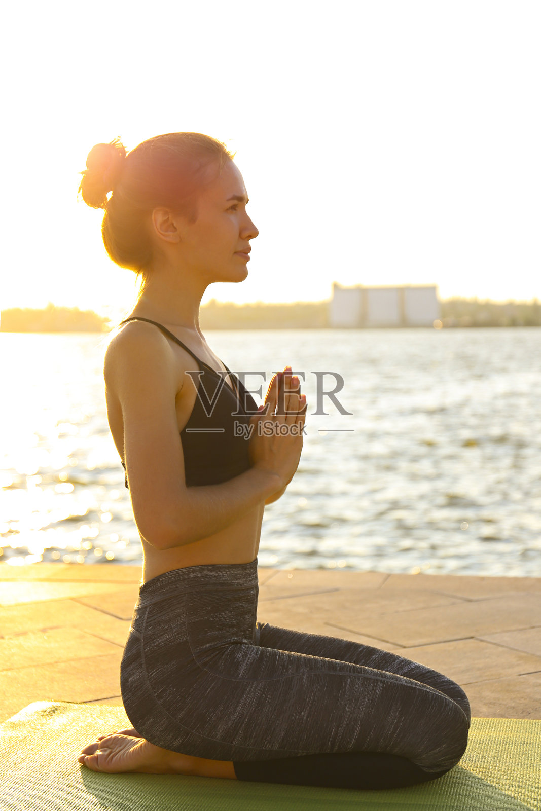 女瑜伽教练在绿色垫子上伸展。照片摄影图片