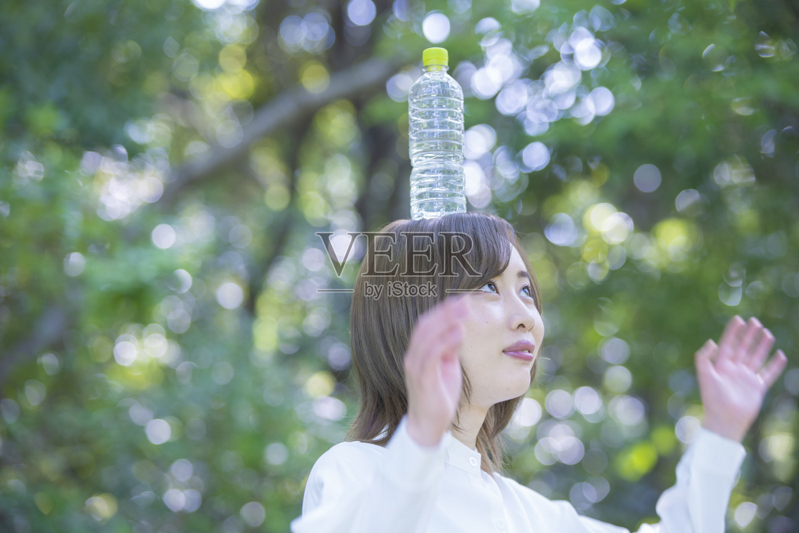 她头上戴着塑料瓶水照片摄影图片