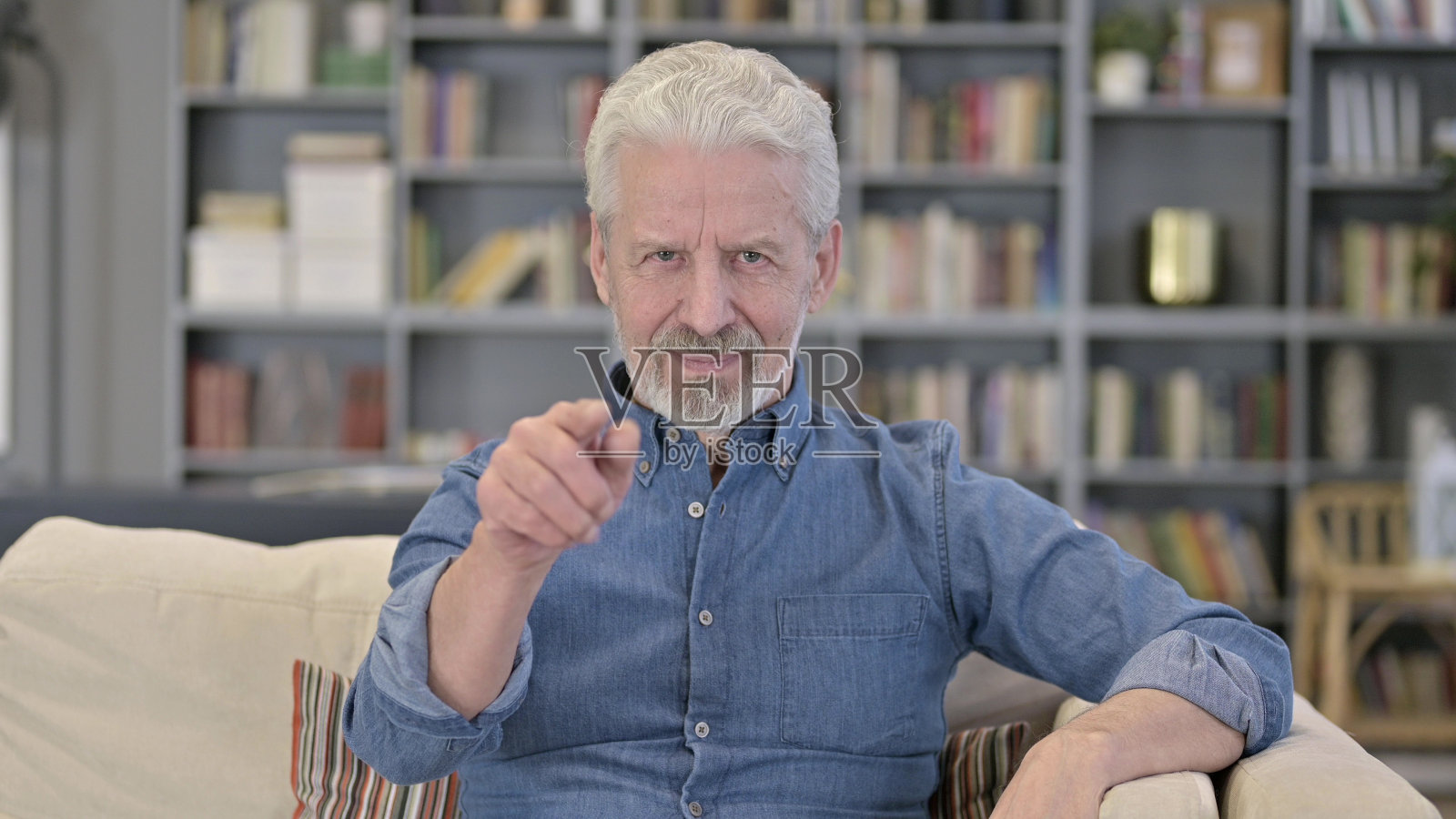 老人的肖像指向相机和邀请照片摄影图片