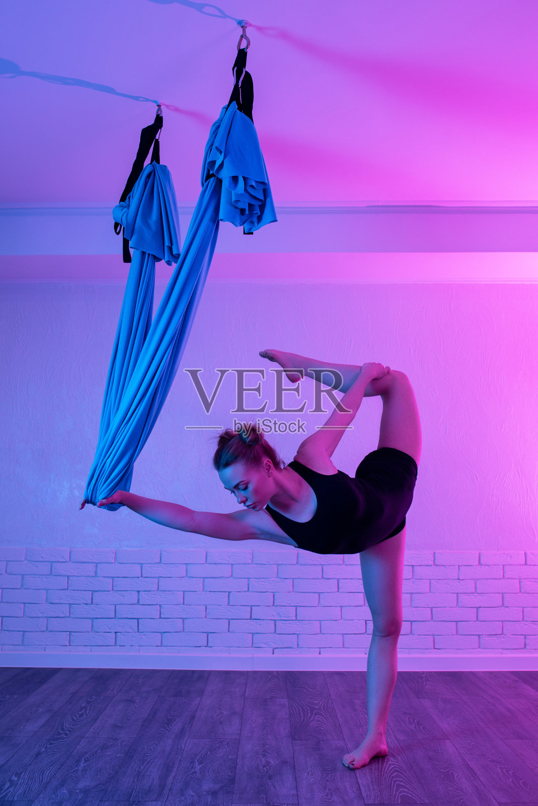 运动年轻女子做重力空中瑜伽拉伸练习瑜伽课。身体和精神之间的平衡。照片摄影图片