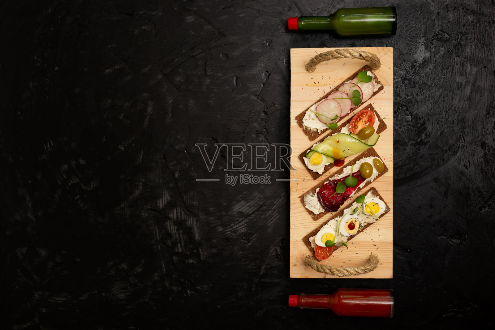 黑麦面包三明治与凝乳奶酪，蔬菜和微型绿色木托盘与酱瓶，俯视图照片摄影图片