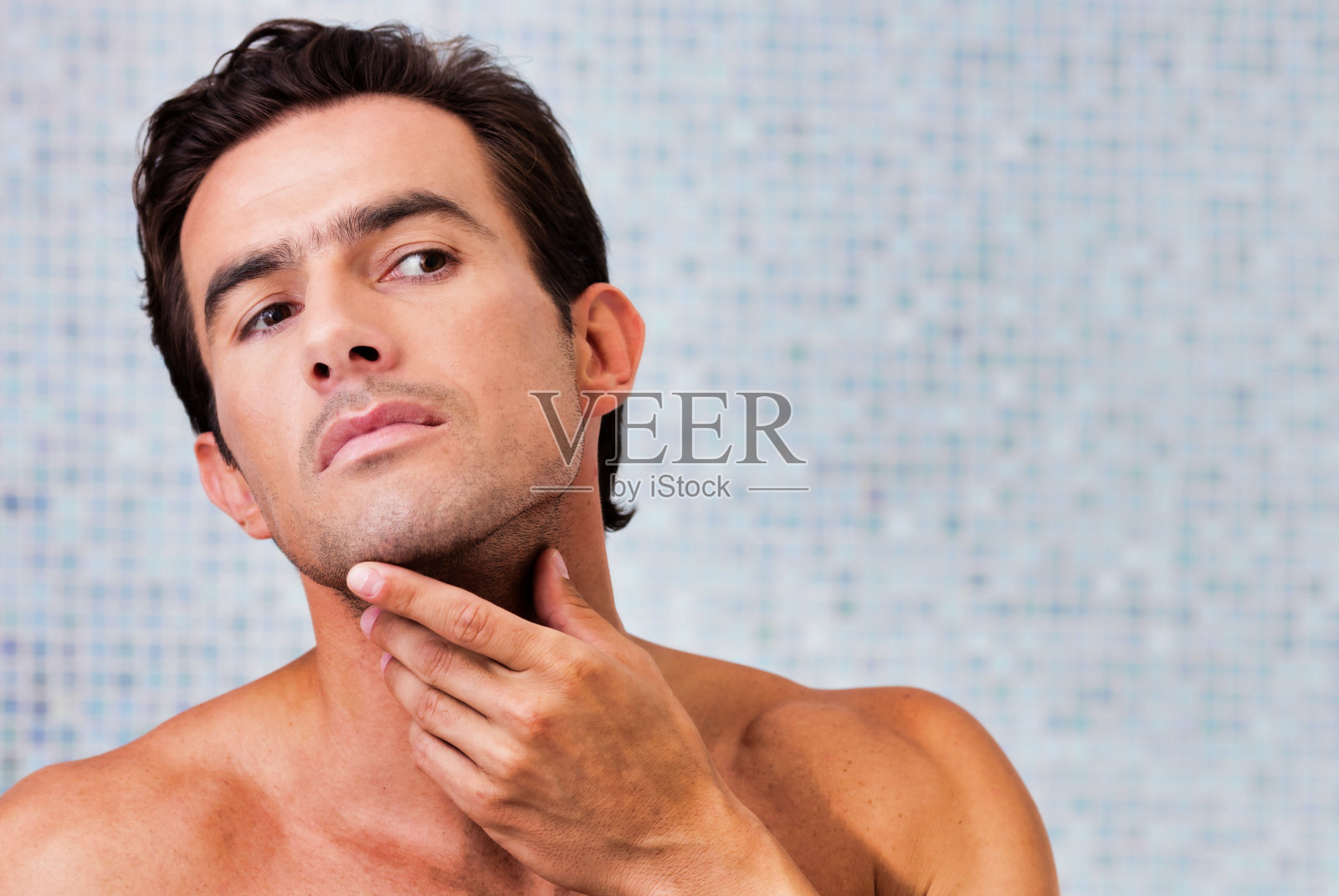 英俊男子对着镜子照脸的肖像照片摄影图片