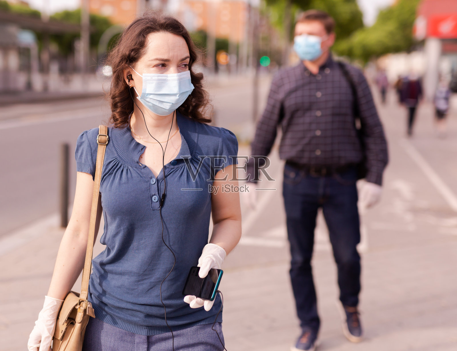 戴医用口罩的女人在城市街道上照片摄影图片