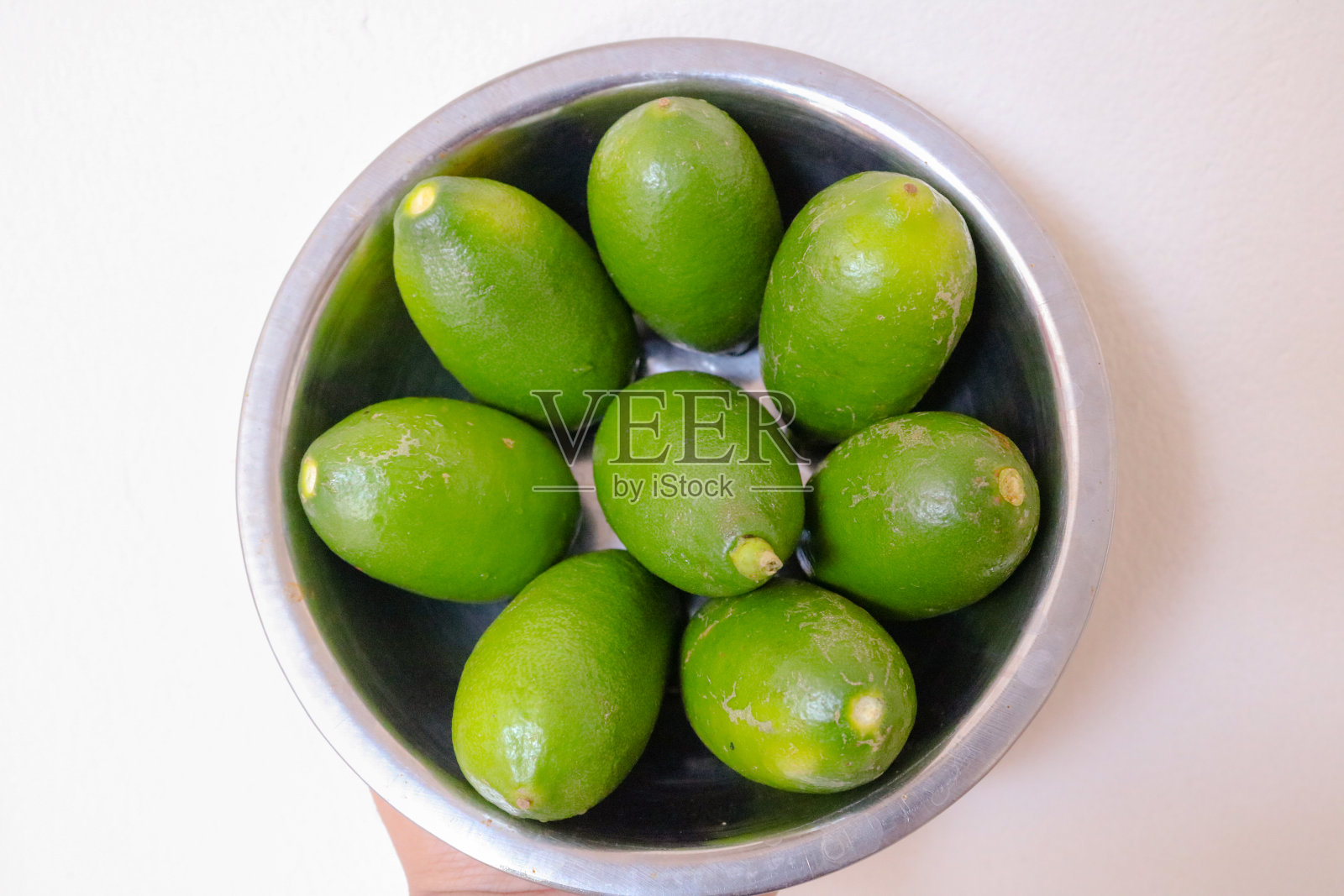 新鲜多汁的绿色柠檬放在钢碗上照片摄影图片