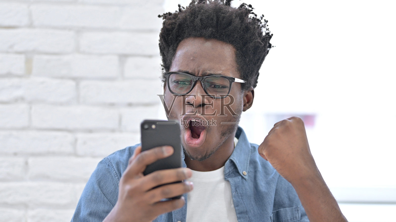 非洲年轻人庆祝智能手机的成功照片摄影图片