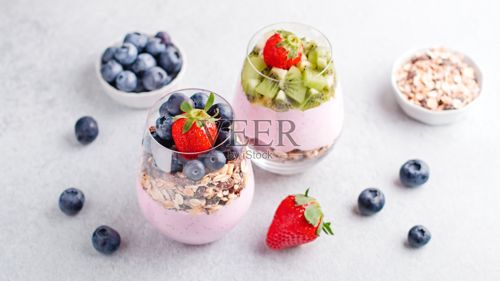 奇亚籽布丁，格兰诺拉麦片，蓝莓和草莓在玻璃杯里。酸奶加奇亚籽，浆果，猕猴桃和什锦早餐，复制空间照片摄影图片