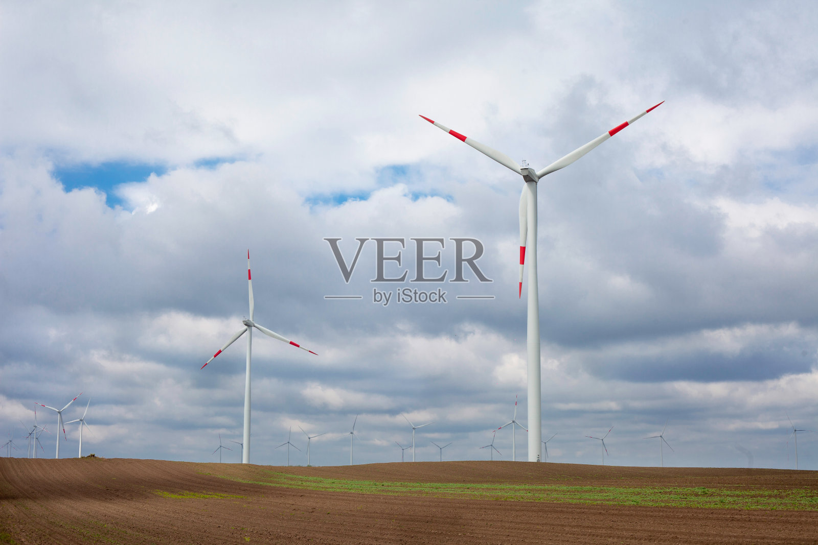 风电场里的风力涡轮机在多云的天空下照片摄影图片