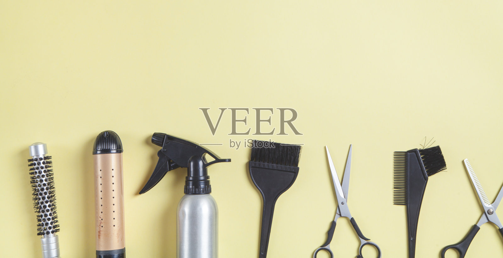剪刀，梳子和其他头发造型工具在黄色的背景。照片摄影图片