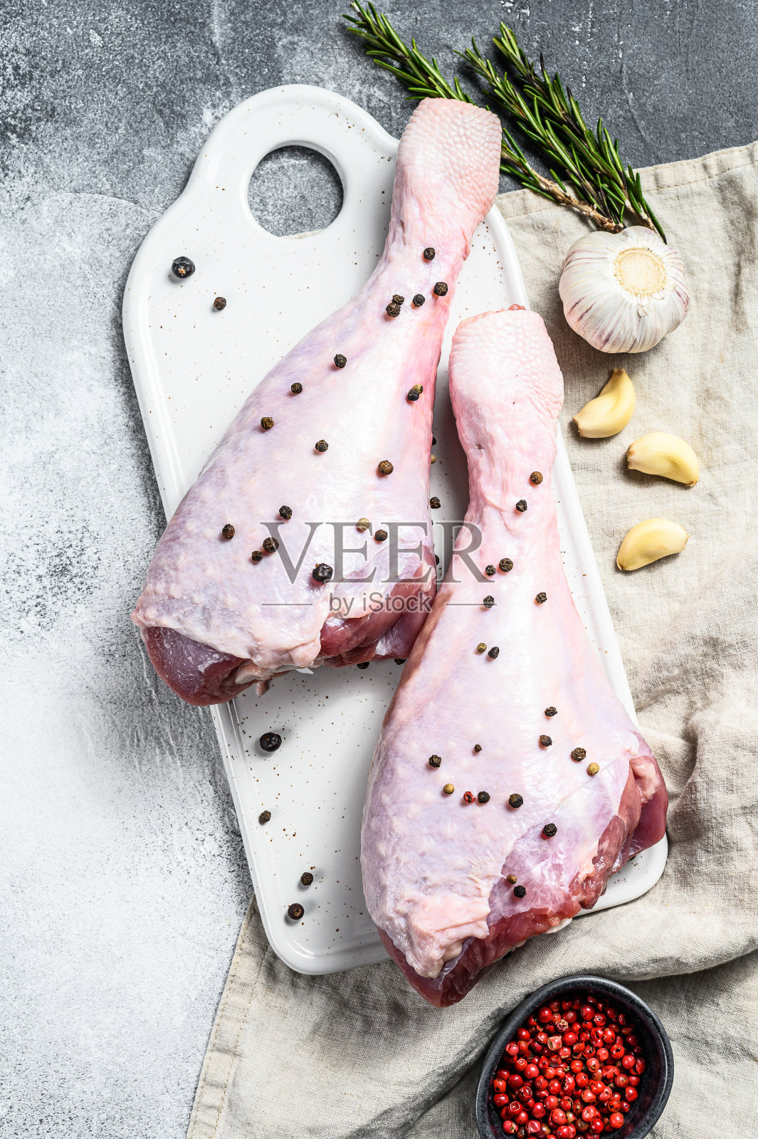 白砧板上放有香料的生火鸡腿。灰色的背景。俯视图照片摄影图片