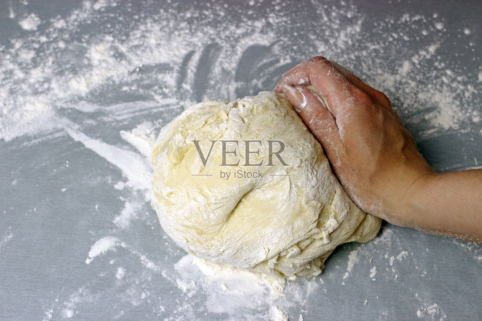 一个女人在灰色的桌子上揉着甜酵母面团照片摄影图片