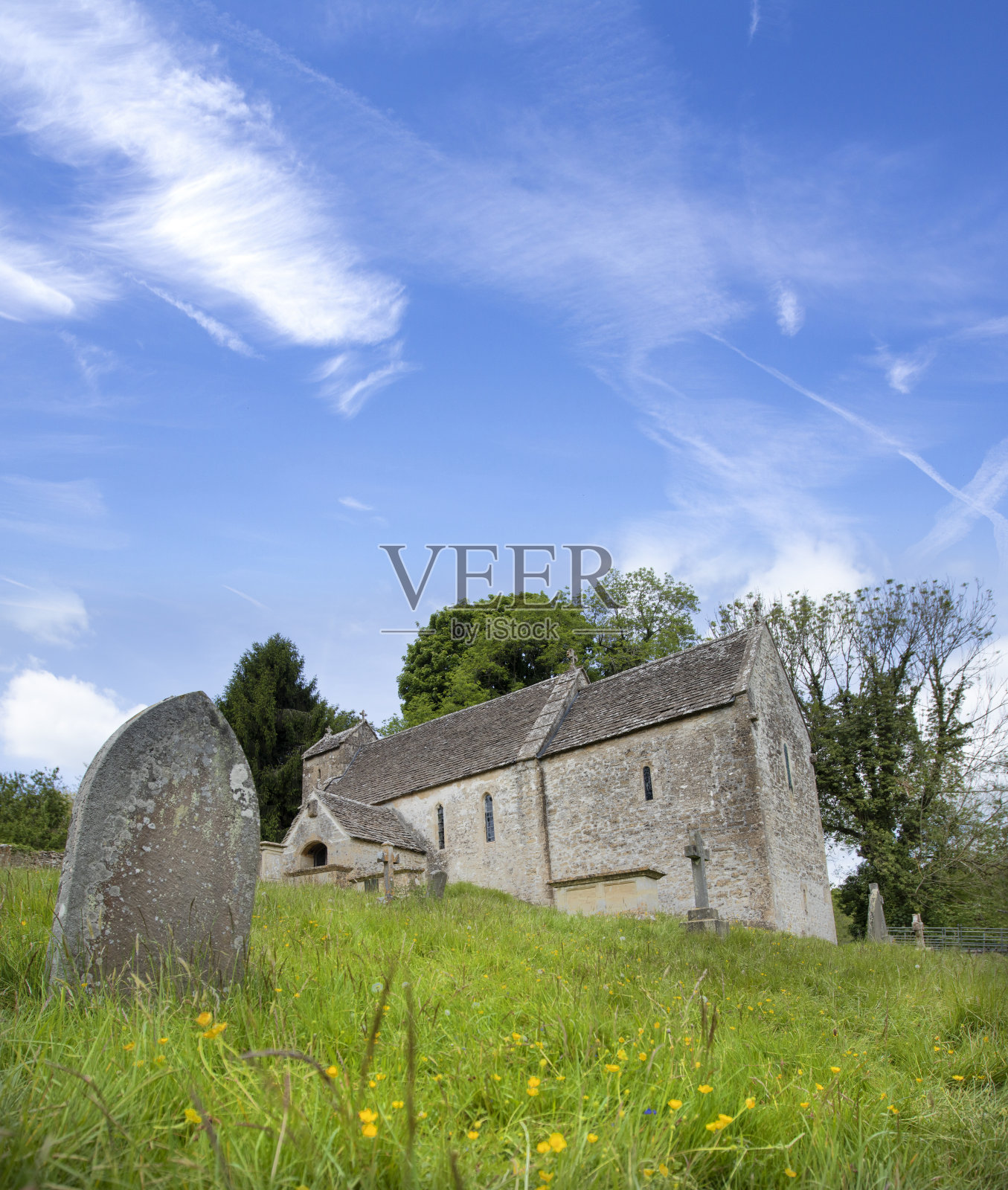 阳光明媚的春日，科茨沃尔德郡赛伦塞斯特附近的登茨伯恩劳斯的圣迈克尔老撒克逊教堂的外景。照片摄影图片