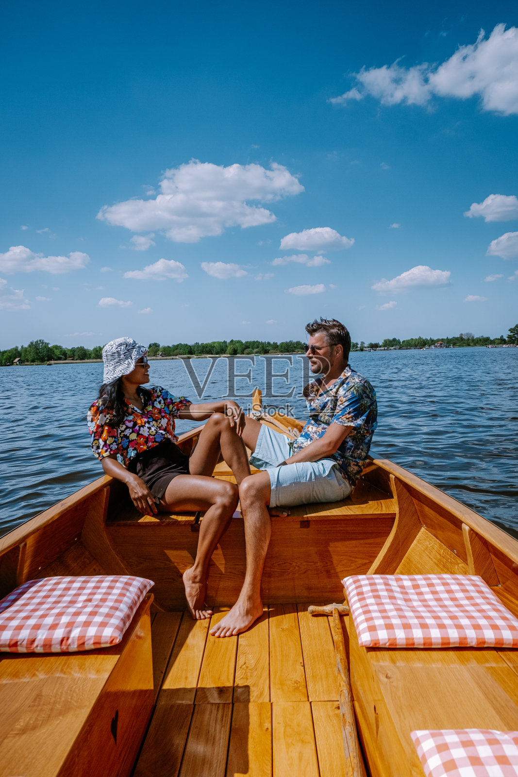 荷兰夫妇Giethoorn乘船参观了这个村庄，在一个炎热的春日里，他们可以看到著名的村庄，有运河和乡村茅草屋顶的房子照片摄影图片