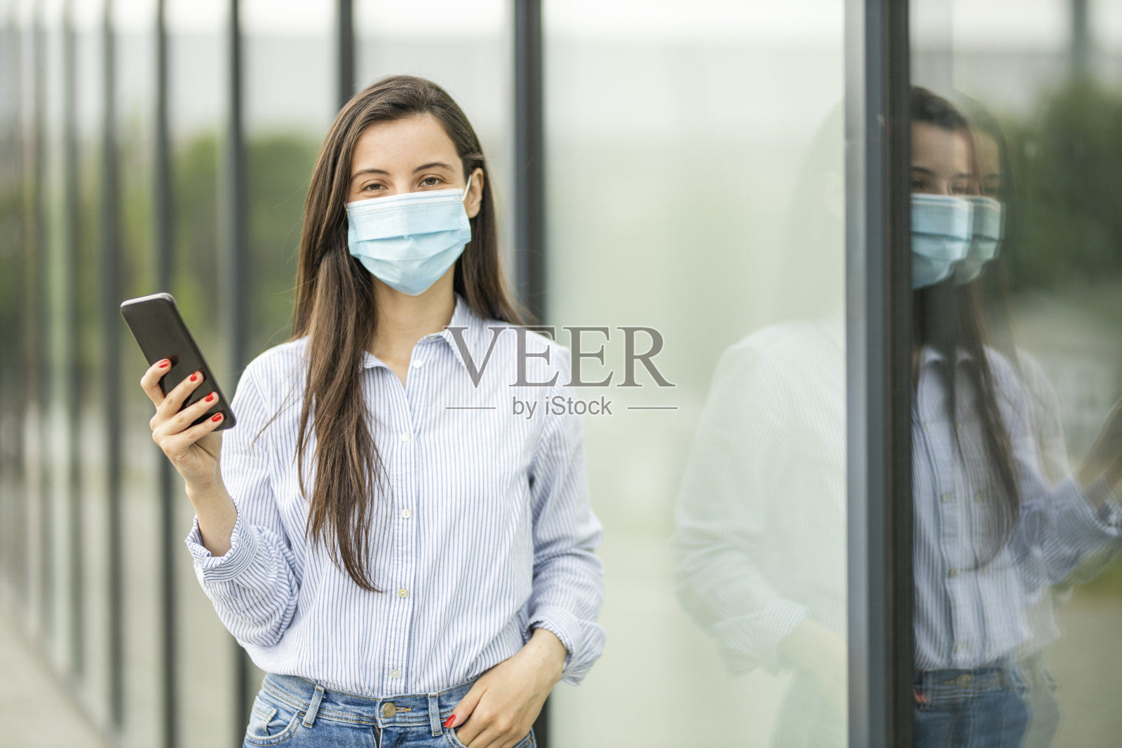 妇女戴着防护口罩，使用手机照片摄影图片