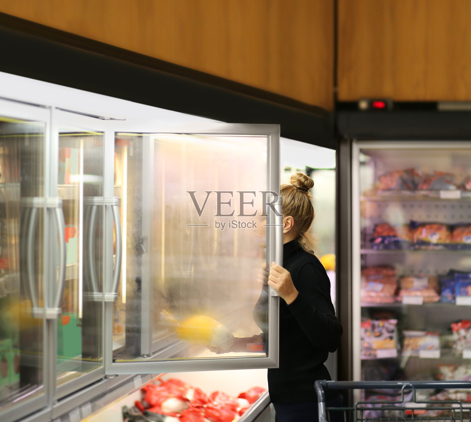 从超市冰箱里挑选冷冻食品的女人照片摄影图片