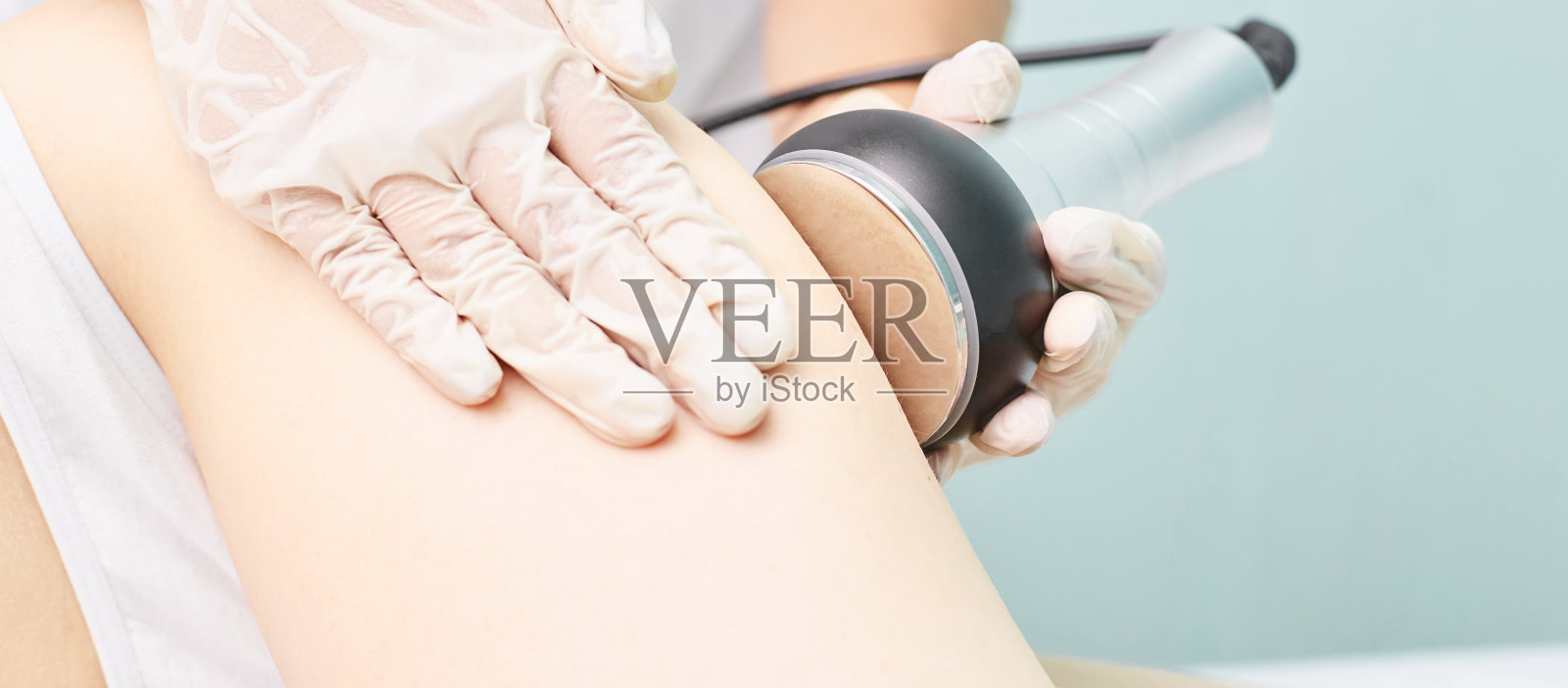 空化体处理。女性超声波抽脂机。Spa轮廓。医生的手照片摄影图片