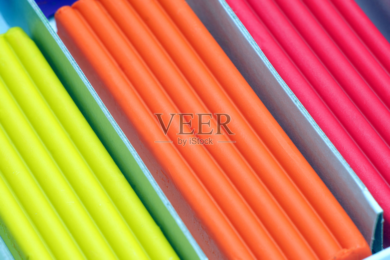 黄色、橙色和红色的橡皮泥粘在纸板箱里。一些高分子塑料粘粘土的特写镜头。照片摄影图片