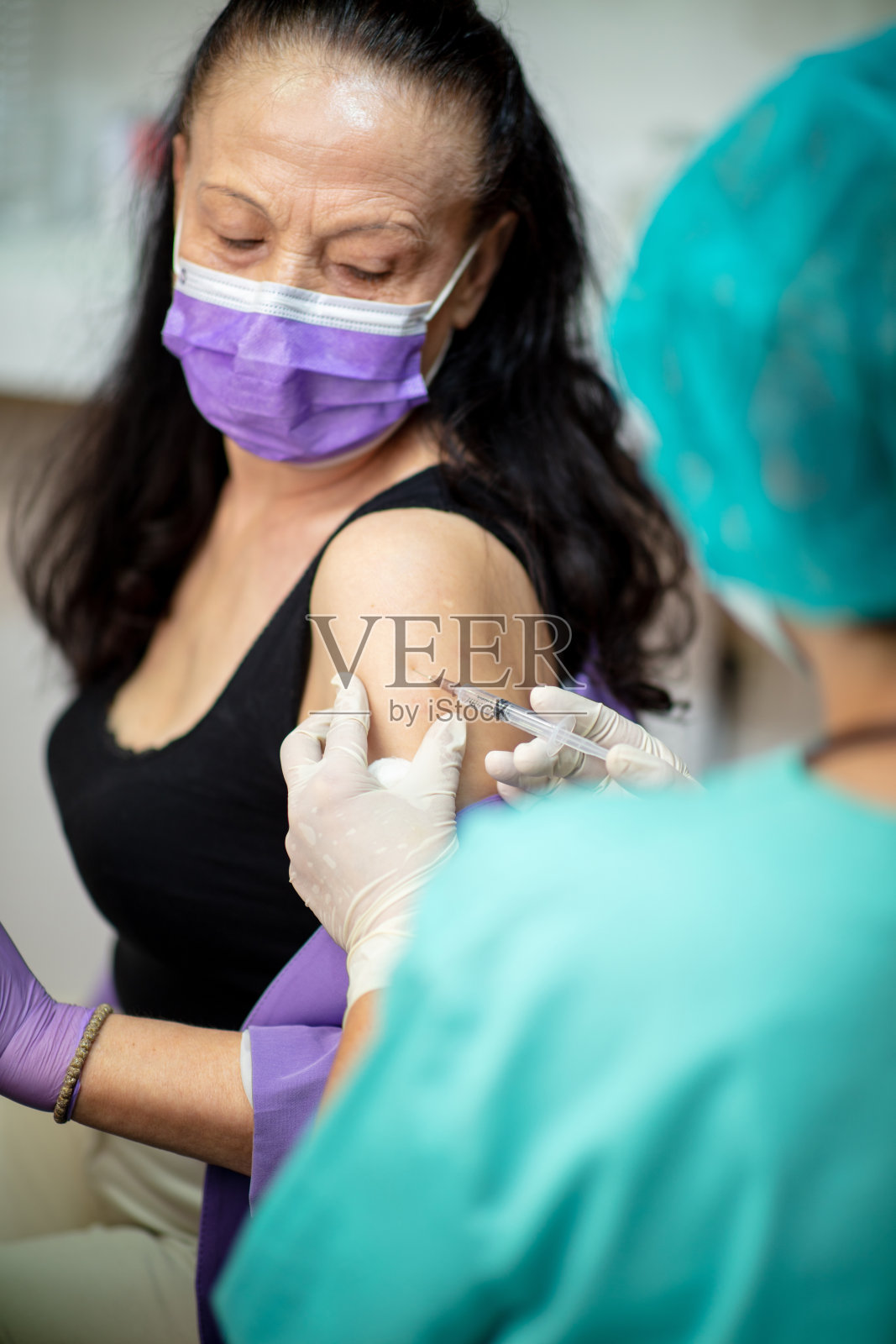 年长妇女戴着防护口罩注射流感疫苗照片摄影图片