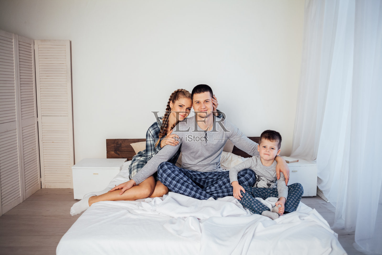 爸爸妈妈和儿子早上躺在家里的床上照片摄影图片