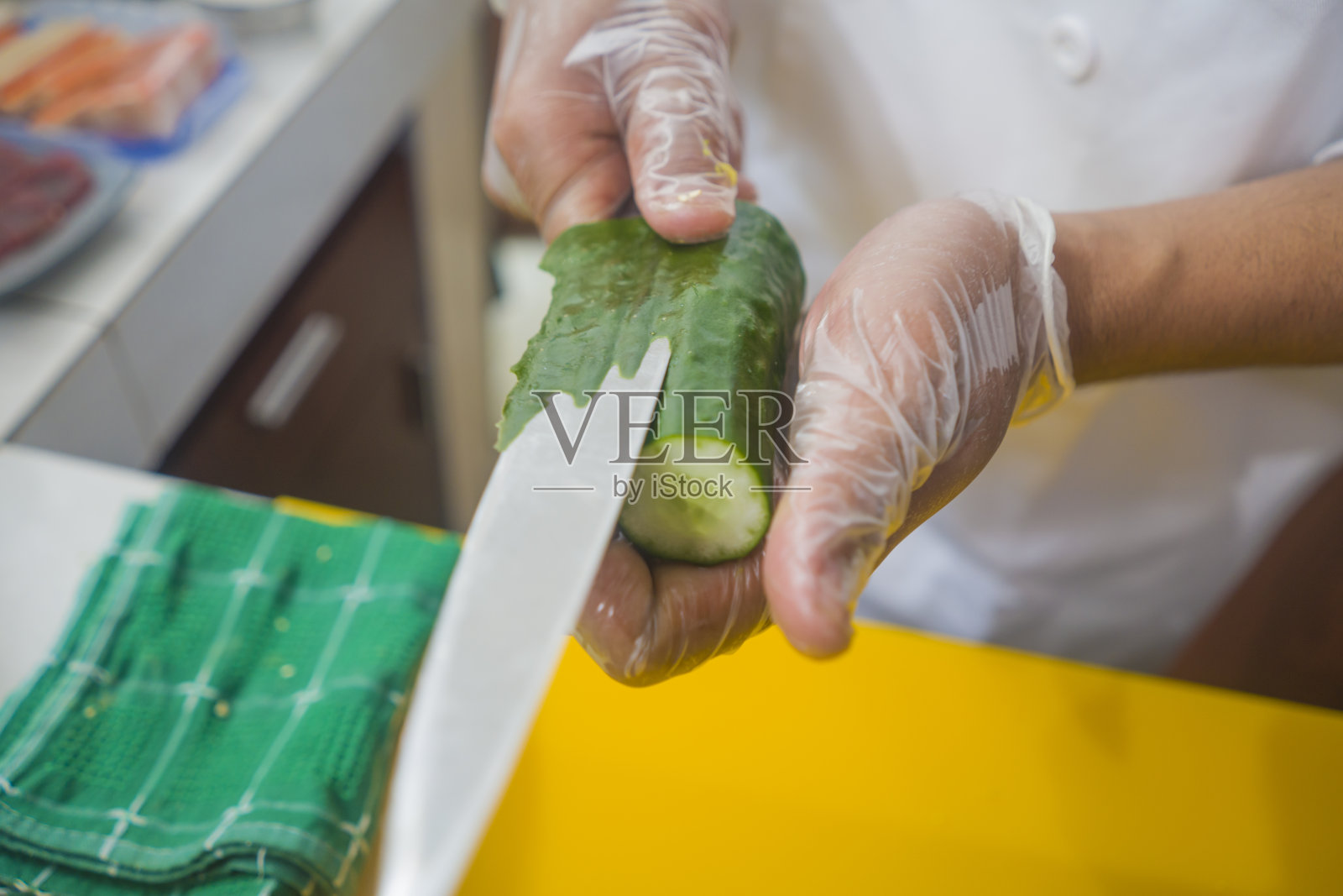 亚洲专业厨师双手手套准备日本寿司卷，用刀切黄瓜在家或餐厅厨房制作传统的日本食物照片摄影图片