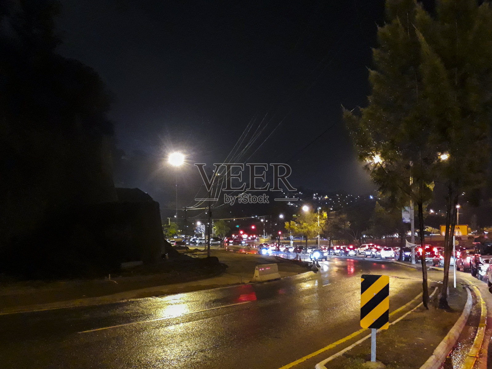 大雨中，危地马拉城市的夜间交通正在建设中。照片摄影图片