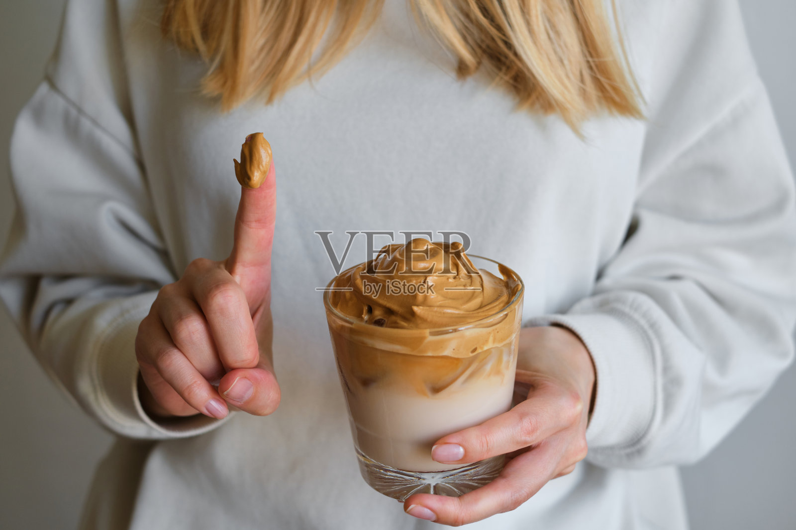 Dalgona咖啡。冷饮加冰。速溶咖啡、砂糖搅打后加入牛奶。女孩手里拿着一杯咖啡。女咖啡师制作美味的夏季饮料。专业的服务照片摄影图片