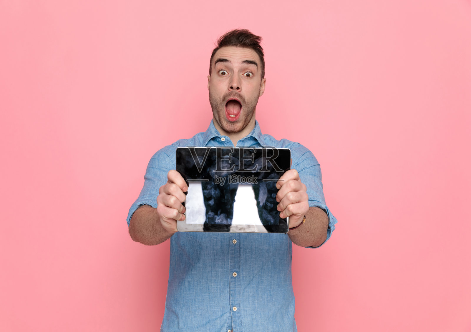 一个漫不经心的人展示着他的平板电脑，张开了他的嘴照片摄影图片