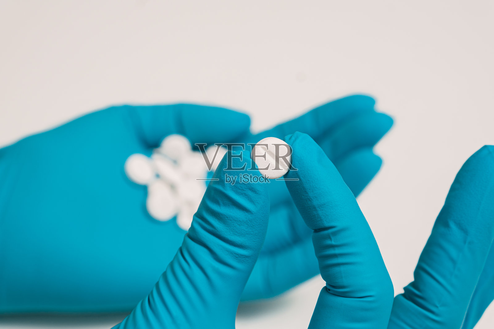 医生戴蓝手套的手拿着药。照片摄影图片