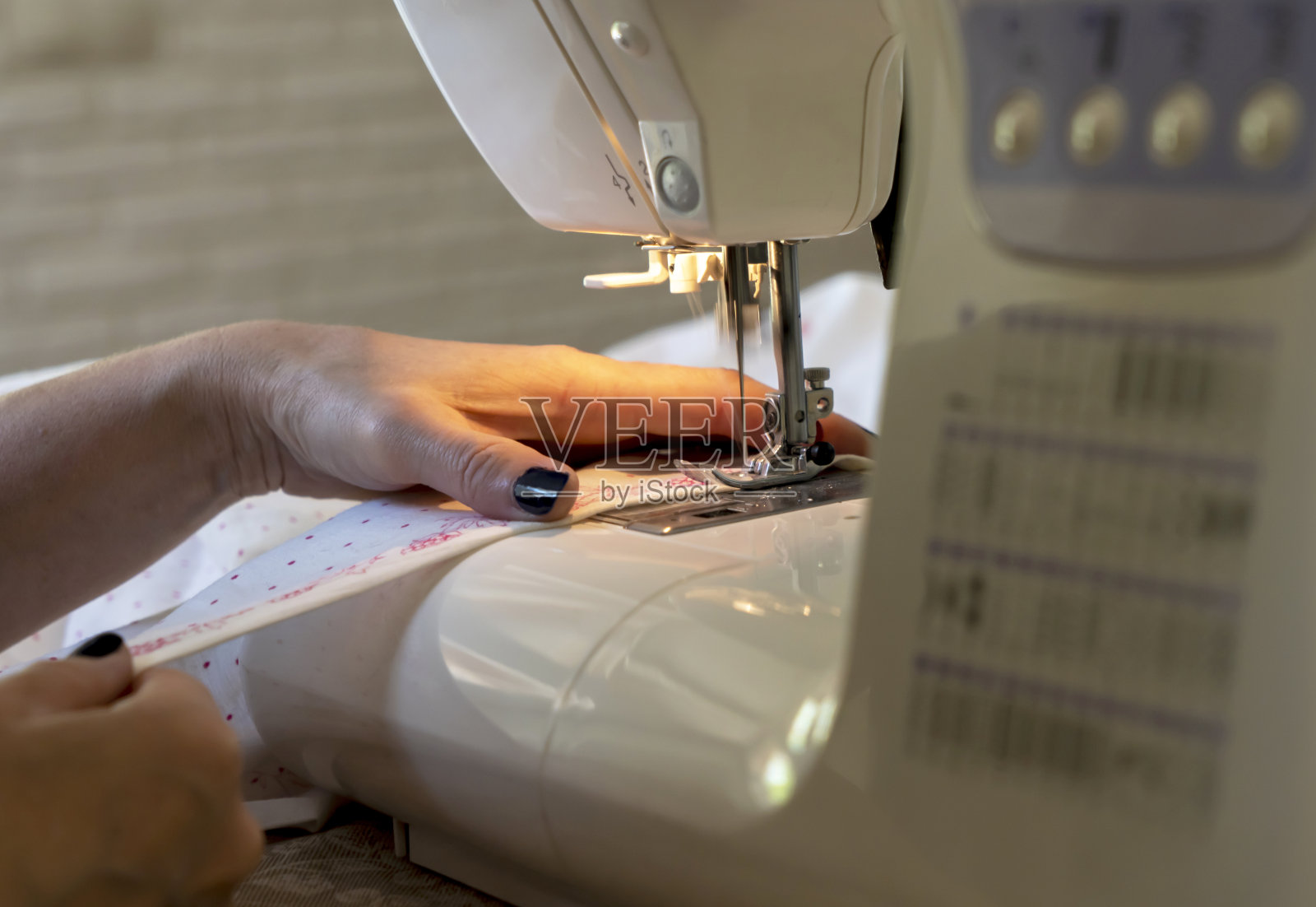 特写女裁缝的手在缝纫机上给布料、衣服下摆照片摄影图片