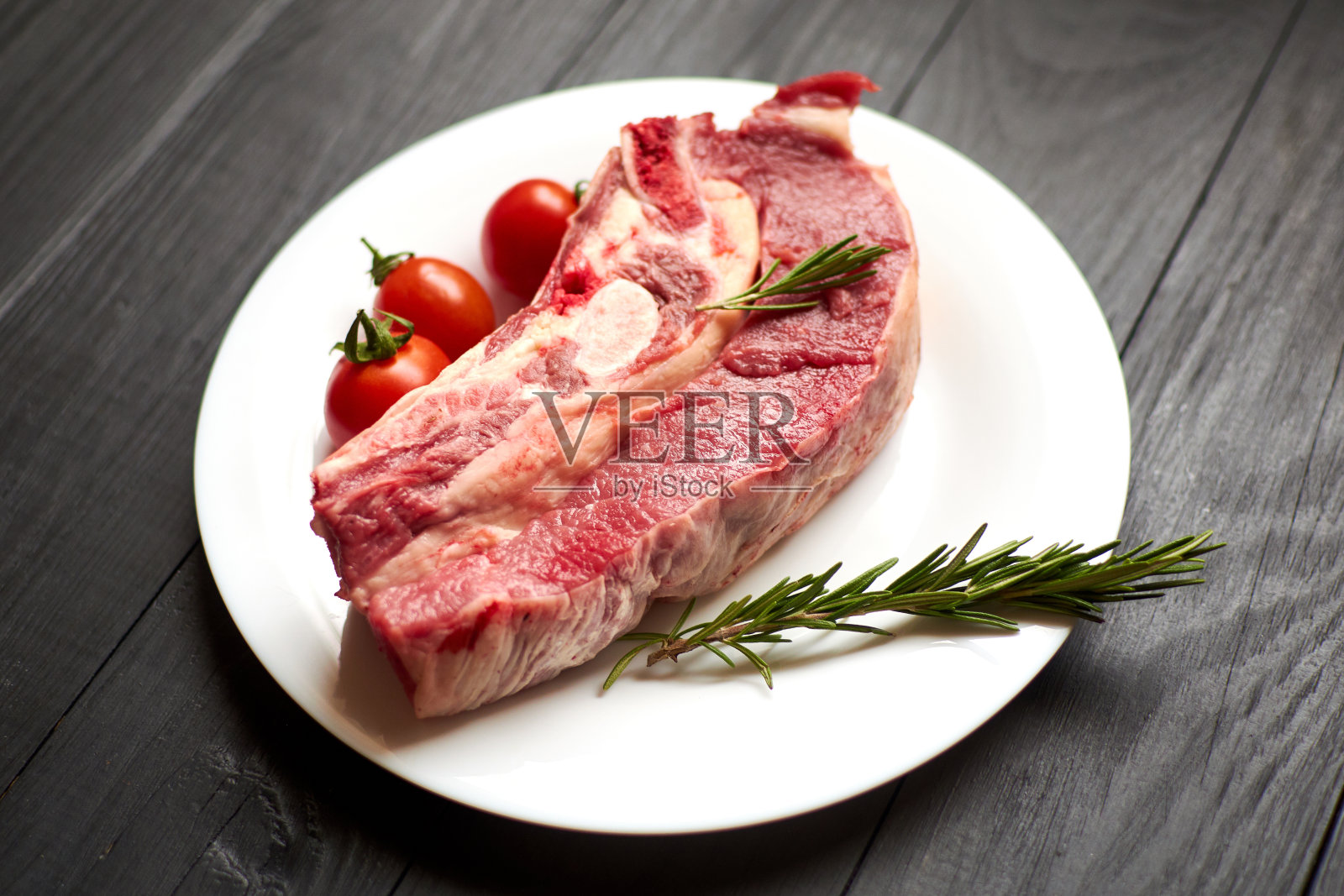 黑木背景的白盘子上的生牛肉。照片摄影图片