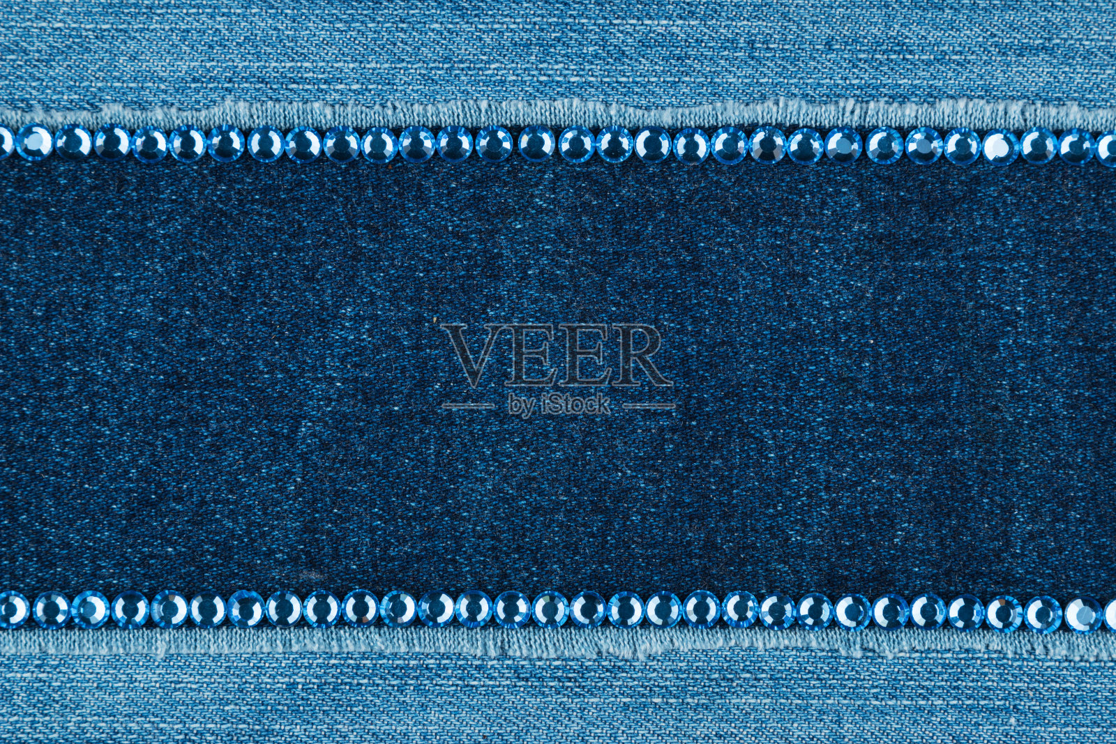 在牛仔布的背景上用蓝色的水钻划出两条线。副本的空间。前视图。照片摄影图片