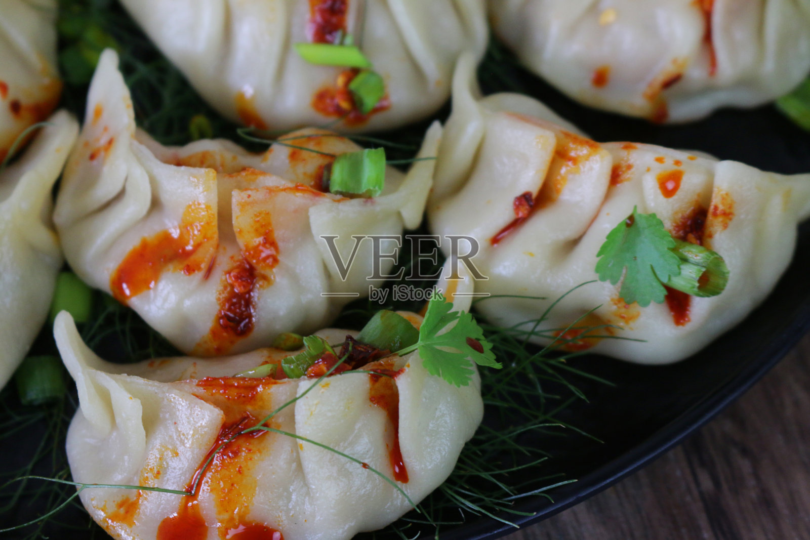 整个画面是蒸饺(南亚饺子)，白面粉和水面团里填满了鸡肉和混合蔬菜，淋上辣椒油，再铺上茴香，再配上葱花和香菜叶，这是一幅俯瞰美景的画面照片摄影图片