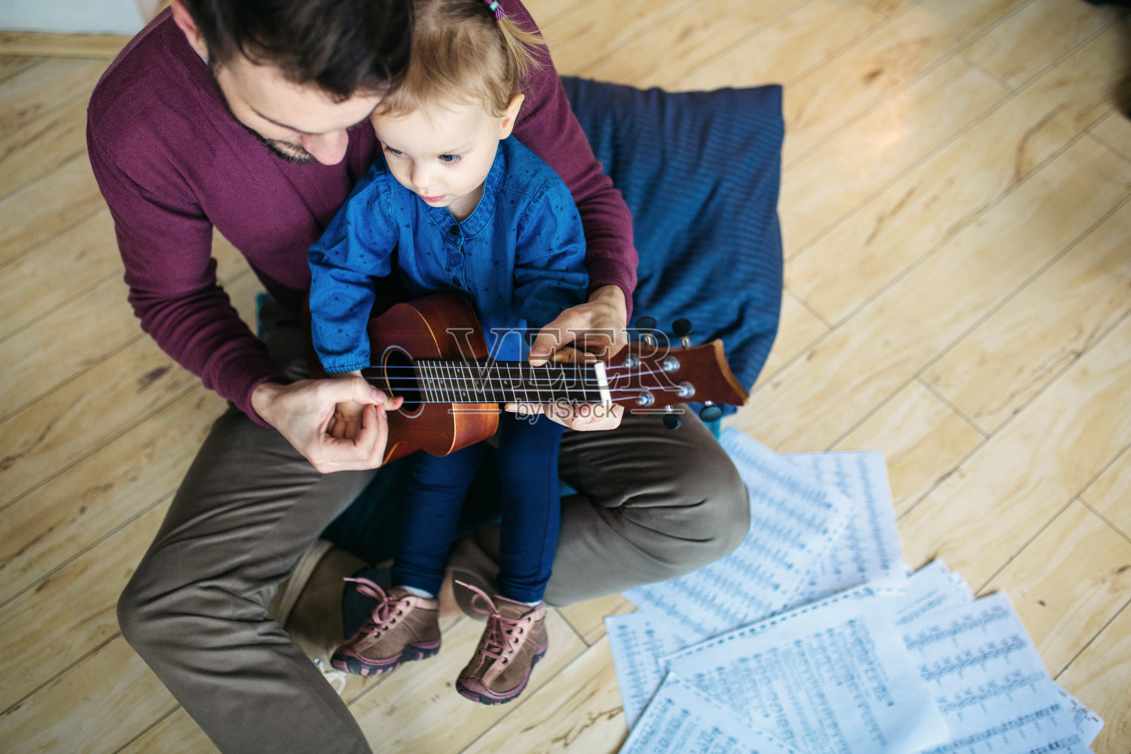 小女孩和她爸爸坐在一起玩尤克里里照片摄影图片