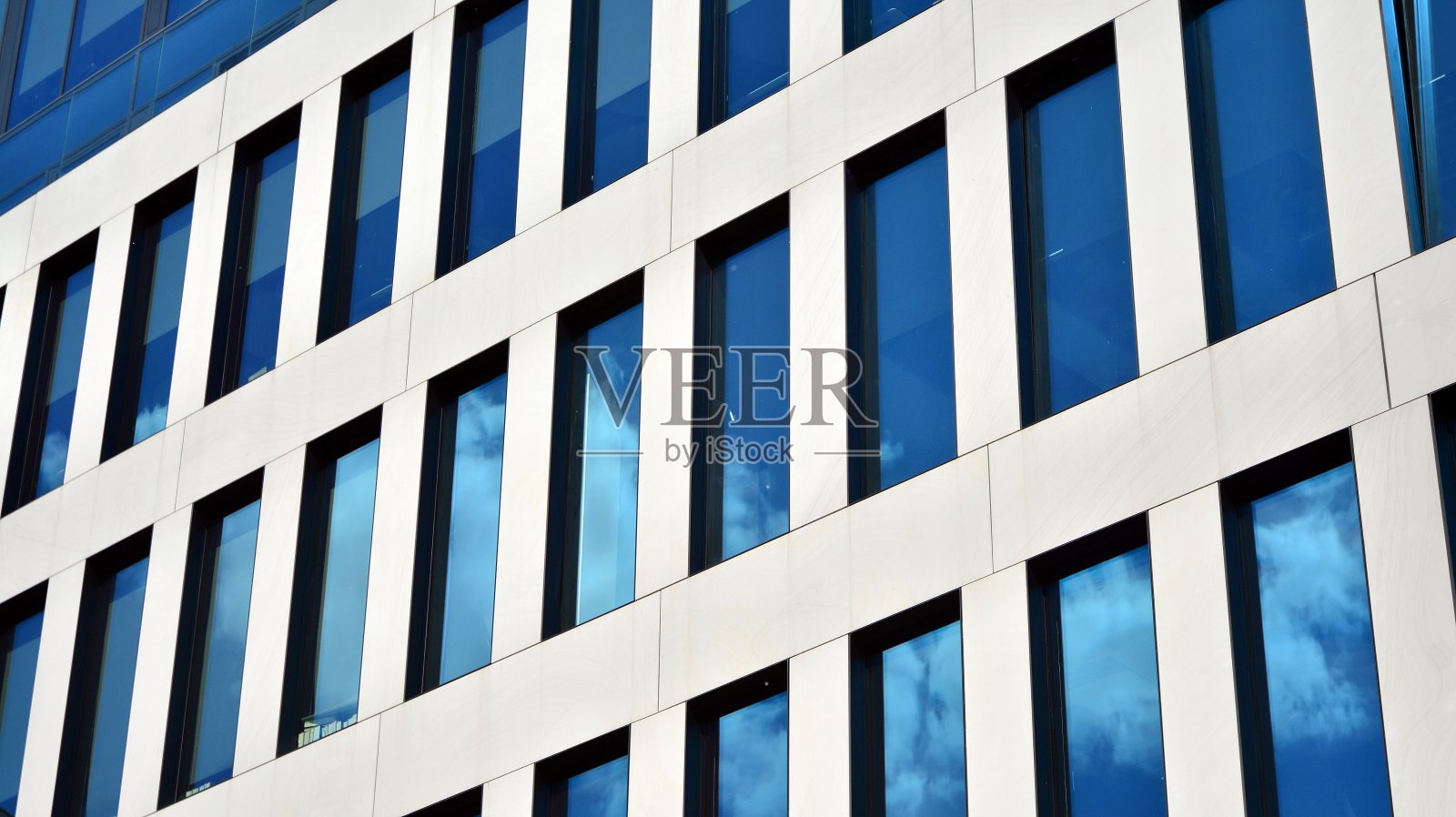 现代办公建筑的窗户具有垂直线条和反射。照片摄影图片