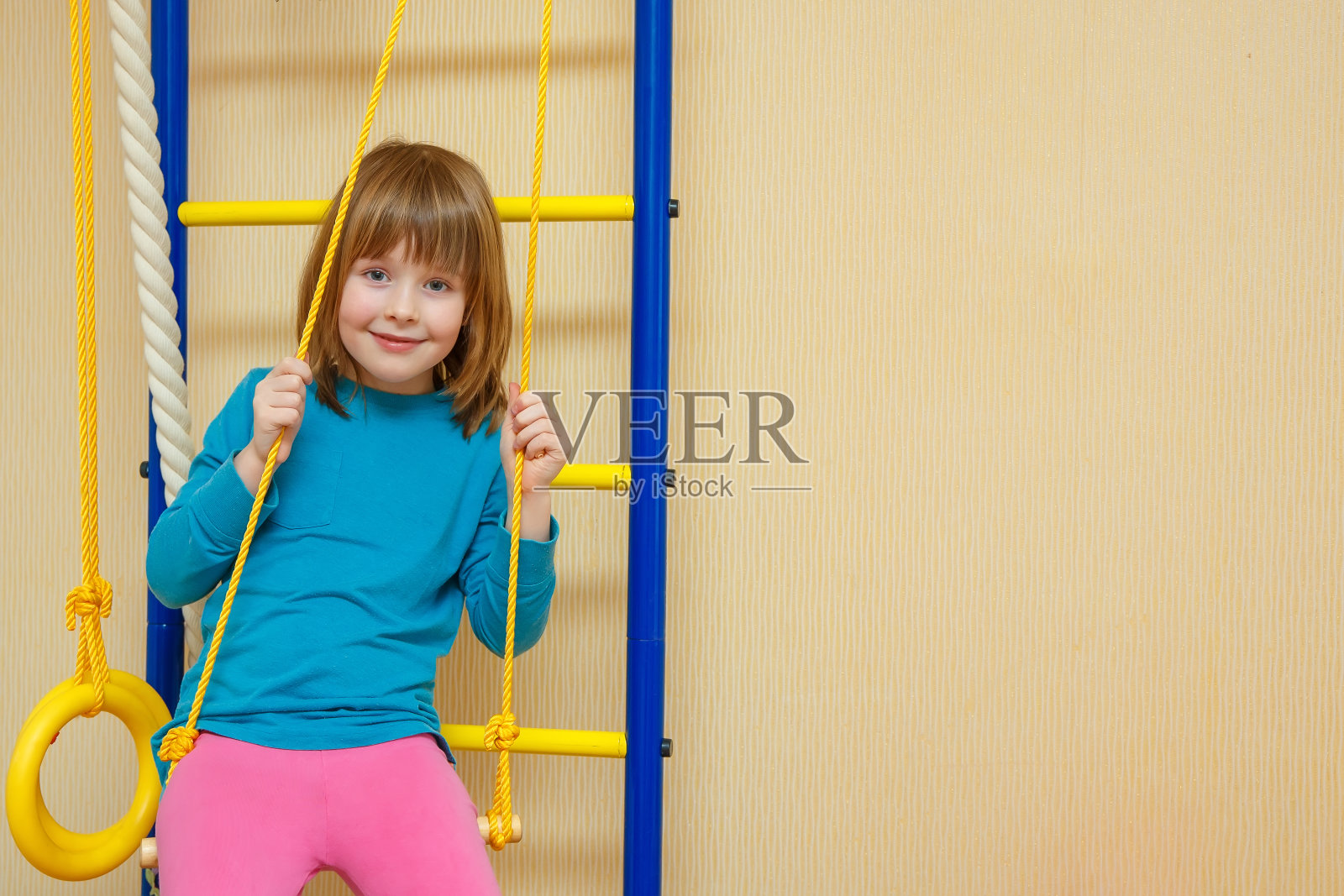 女孩愉快地坐在运动梯子上。照片摄影图片
