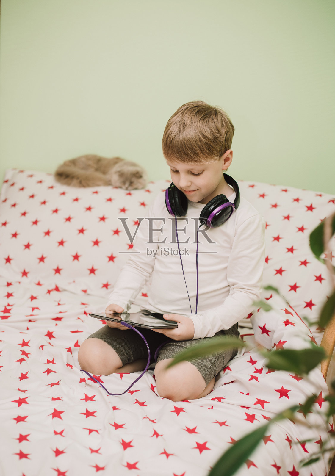 小男孩戴着耳机听音乐。冠状病毒感染期间在家的儿童。远程学习。现代技术照片摄影图片