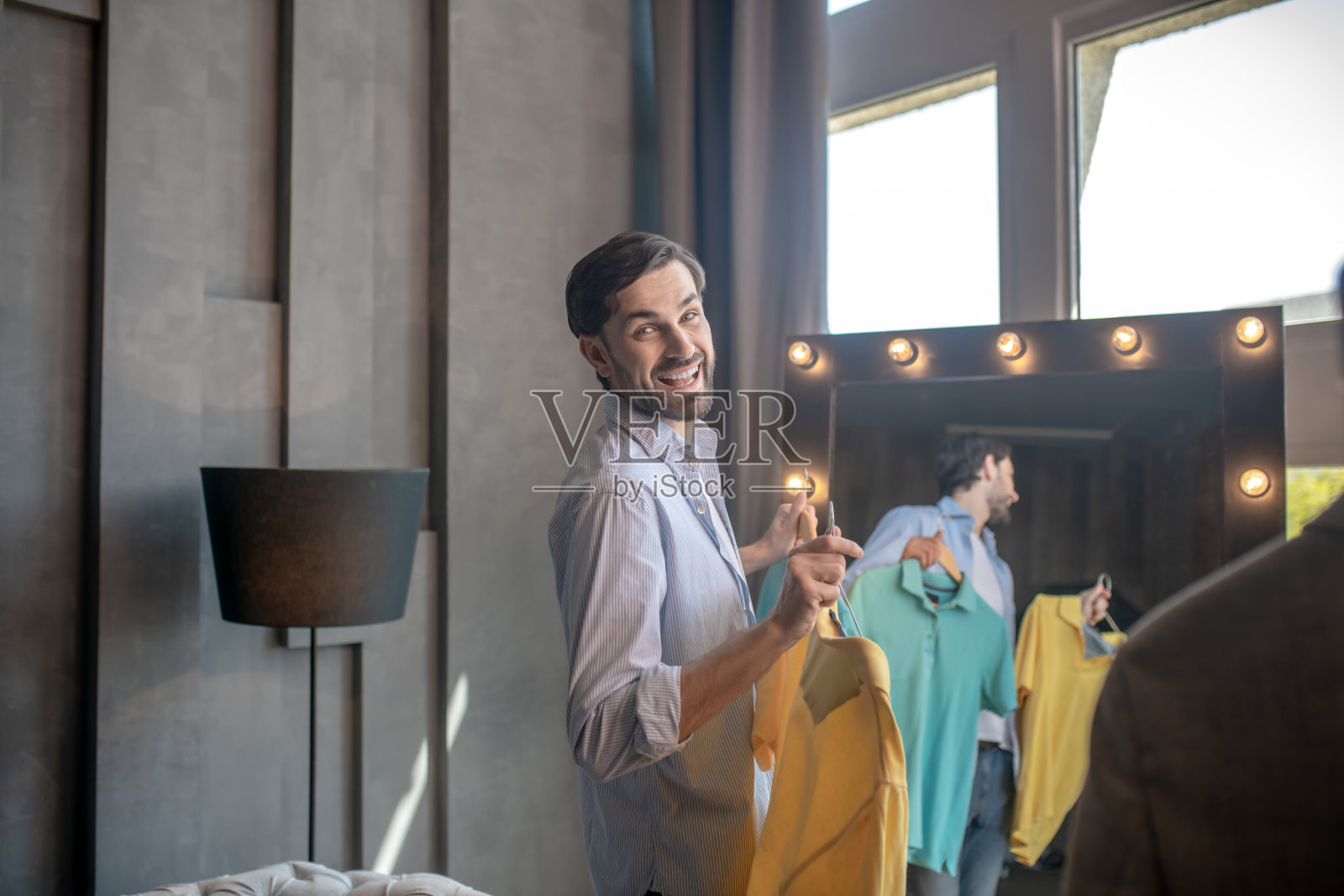 快乐的男人站在镜子前回头看。照片摄影图片