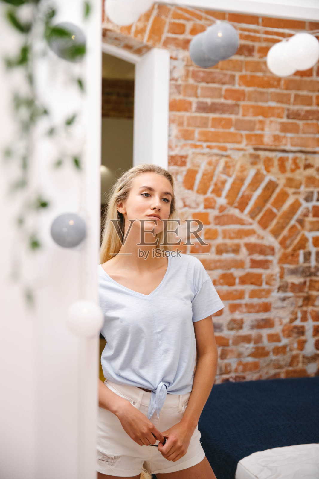 年轻的金发女人在家照镜子。照片摄影图片