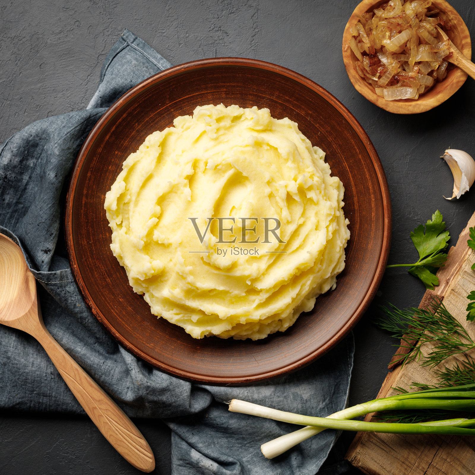 土豆泥，煮成泥，放在棕色的盘子里，背景是黑色的石板。照片摄影图片