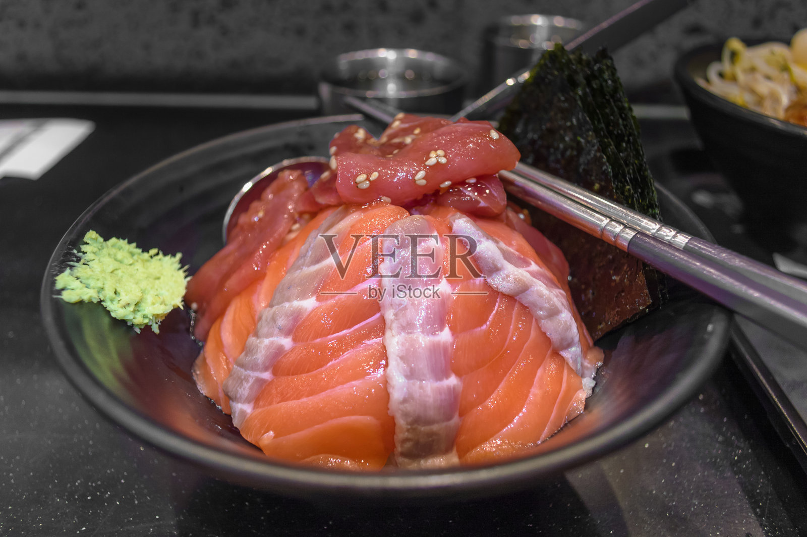 新鲜的米饭上覆盖着金枪鱼片和鲑鱼片，还有芥末和海苔照片摄影图片