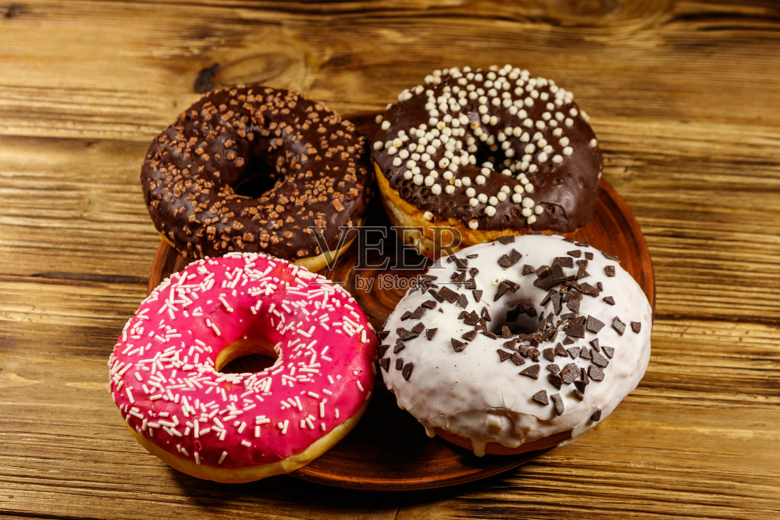 美味的甜甜圈放在盘子里放在木桌上照片摄影图片