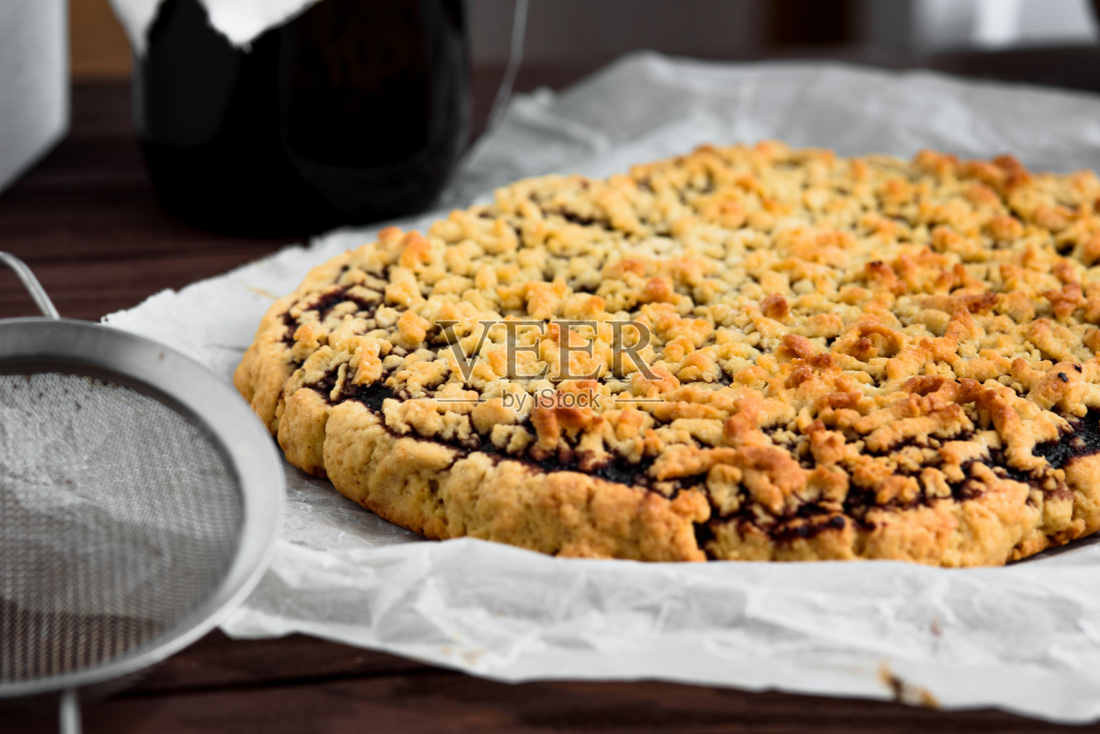 在一张羊皮纸和一个小筛子在前景磨碎的派。派放在旁边。照片摄影图片