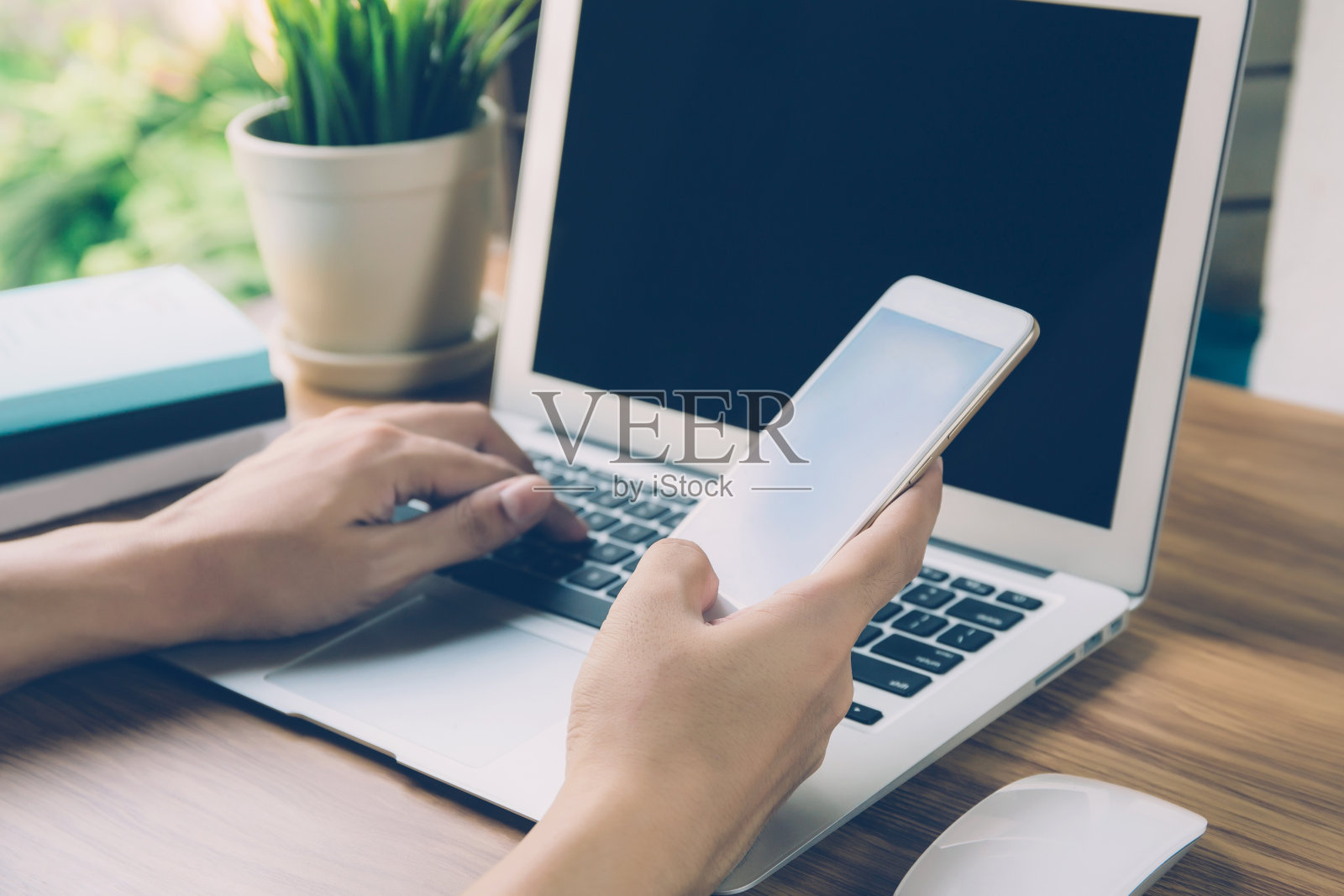 用笔记本电脑在家工作的商人手在桌上上网，新常态的生活方式，社交距离，自由职业者在家里工作，看电话，交流的概念。照片摄影图片