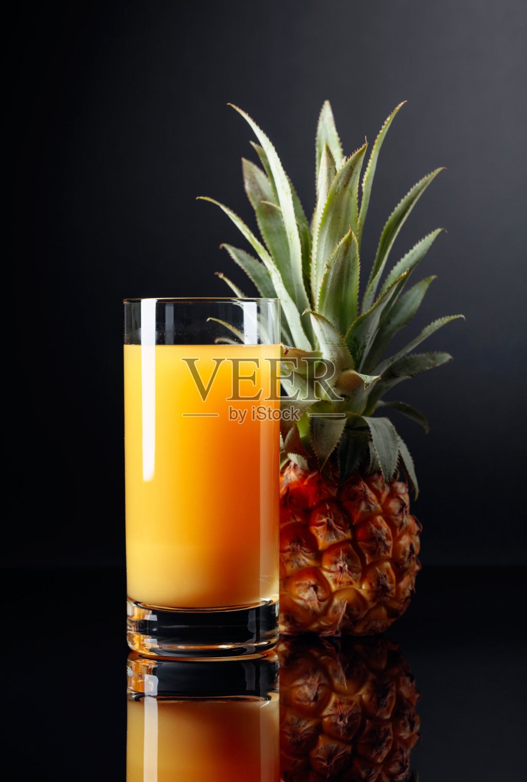 黑色背景上的菠萝和果汁。照片摄影图片