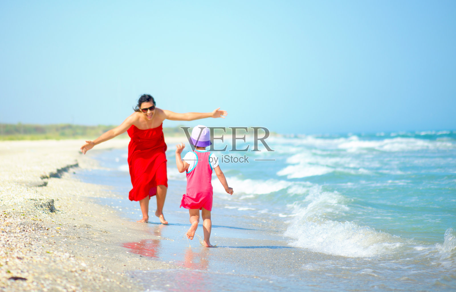 妈妈和她的小女孩在海边玩耍照片摄影图片