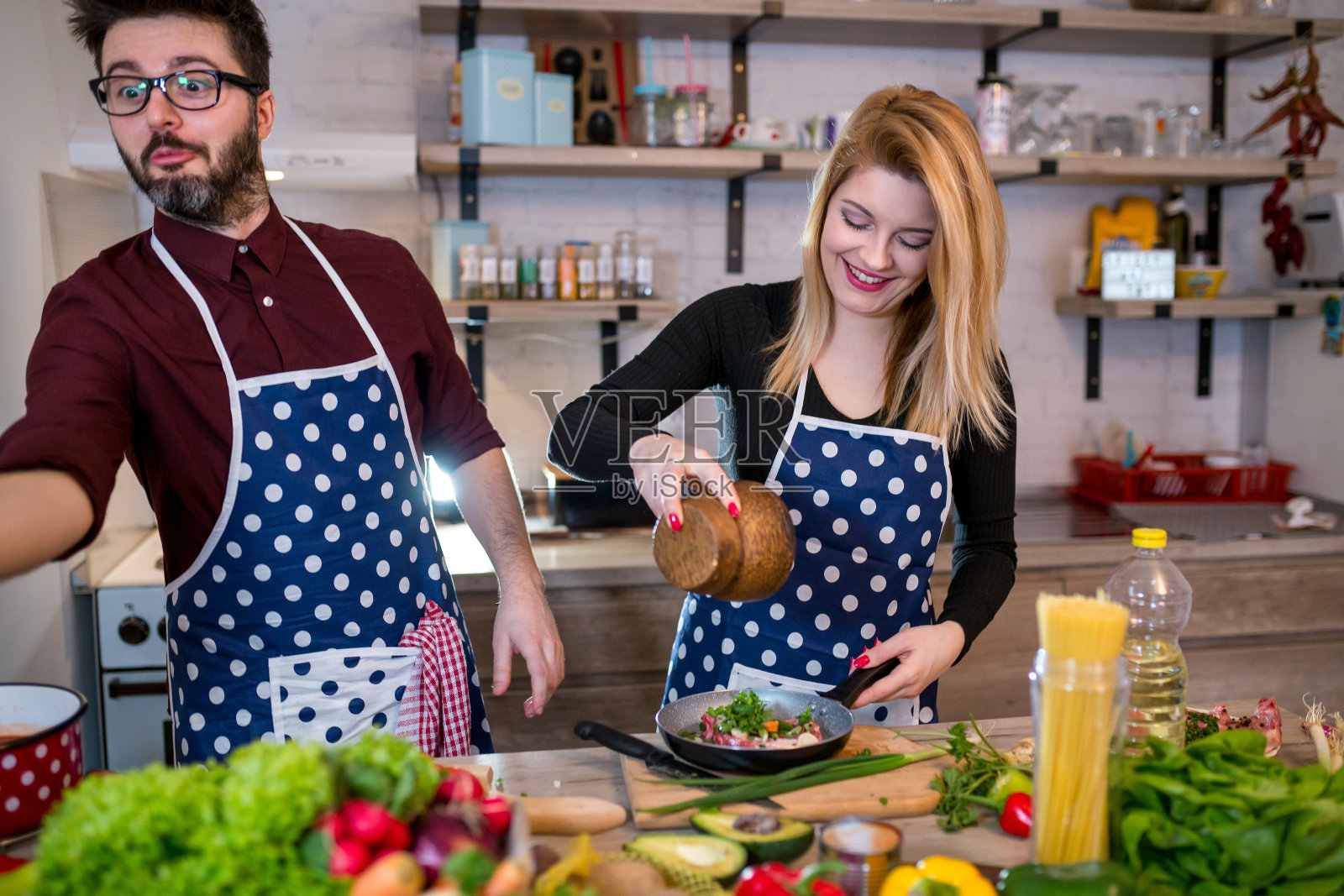 微笑的年轻夫妇在厨房做饭照片摄影图片