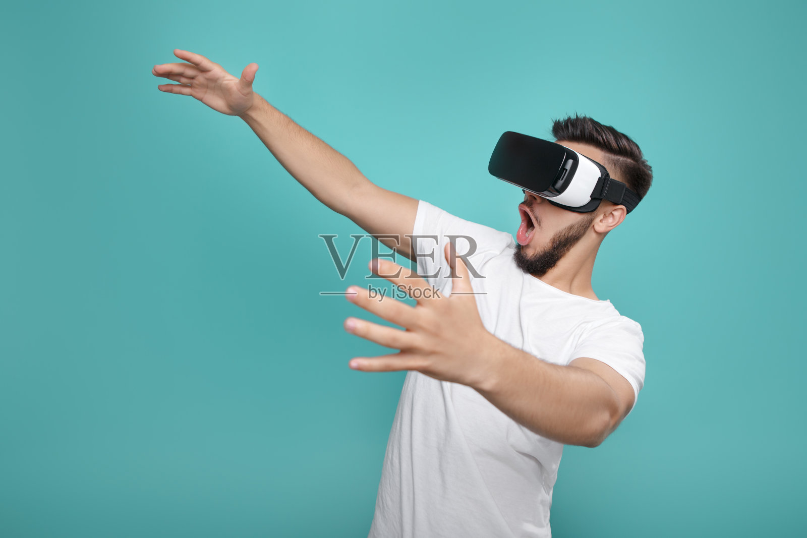 英俊的胡子男子尝试VR耳机和探索另一个世界在多彩的背景。照片摄影图片