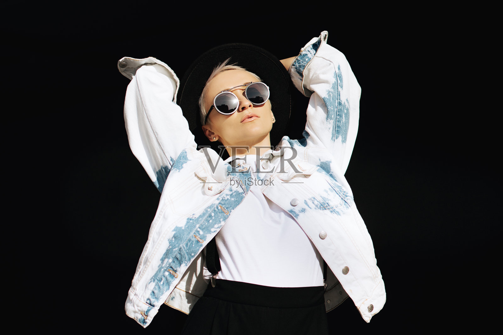 快乐迷人的时髦女孩享受闲暇时间。明亮的年轻女子在时尚的服装摆姿势在黑暗的阴影。照片摄影图片