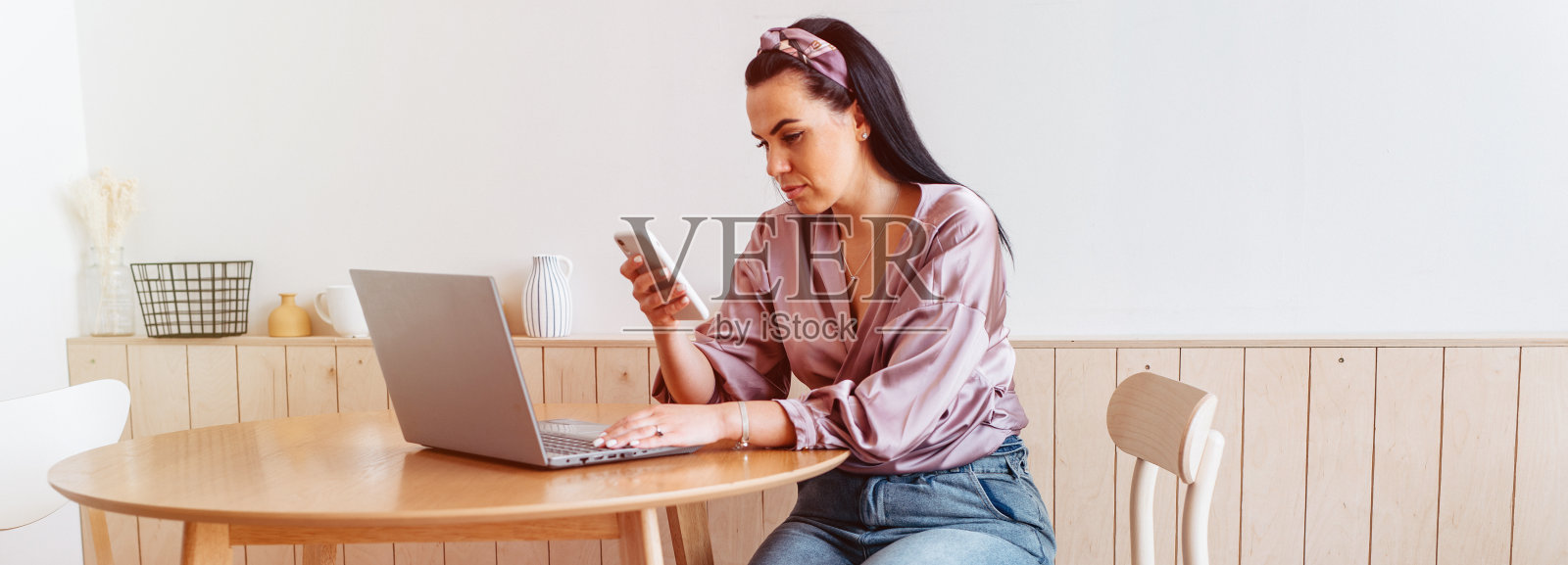 女人在家里工作的笔记本电脑坐在厨房的桌子上，横幅大小照片摄影图片